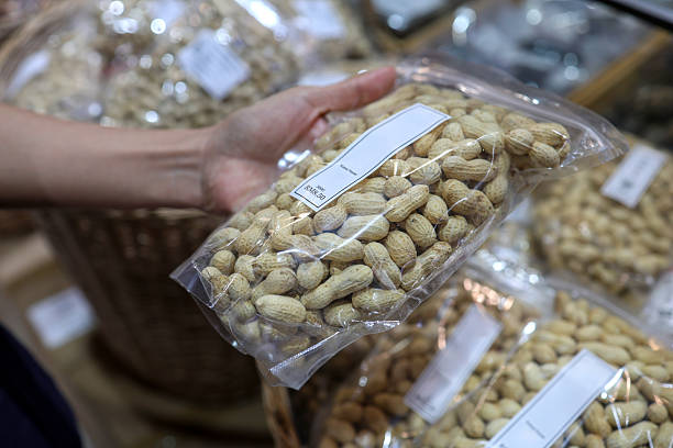 istock Hand holding packed peanuts in plastic bag at grocery store 2234252324