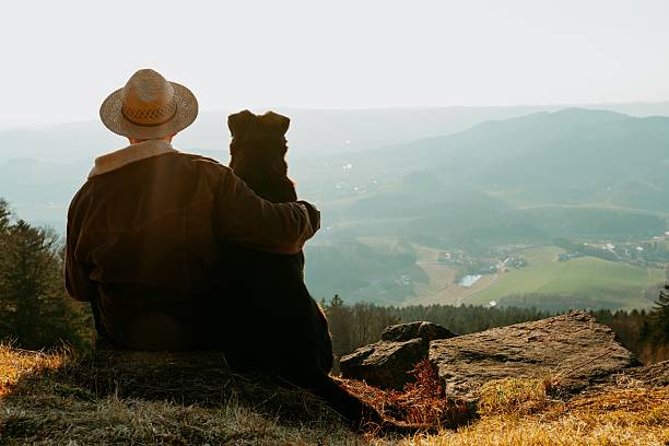 istock Middle Eastern Man in a hat sitting with his dog overlooking a scenic mountain valley at sunset 2234259900