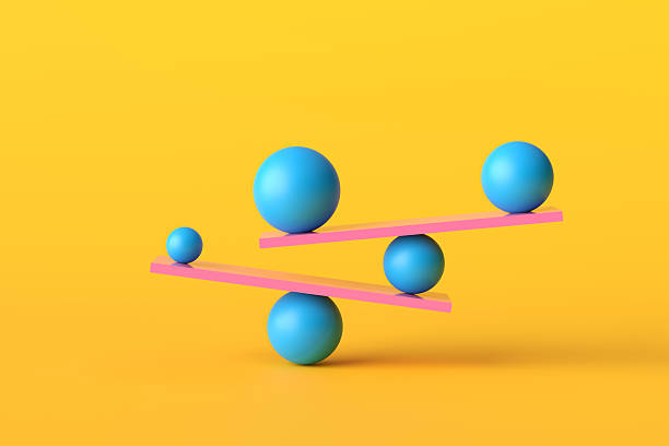 istock Balancing balls of different sizes on pink seesaws creating equilibrium 2234261692
