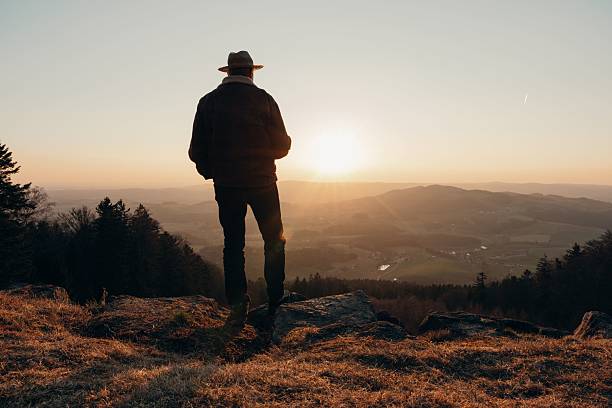 istock A Middle Eastern man in a hat standing on a hilltop watching the sunset over a scenic valley 2234262386