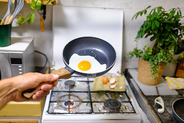 istock Chef holding frying pan with fried egg over stove 2234262566