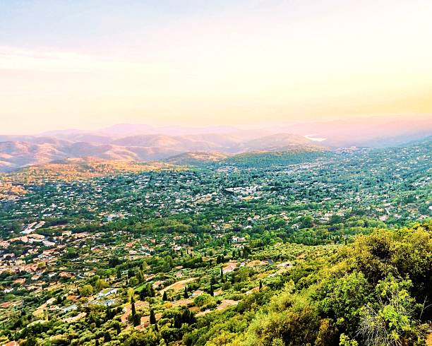 Expansive valley view at sunset from a hillside lookout, with layered mountains, forested towns and a pastel sky. Tranquil Mediterranean panorama suited to travel, lifestyle and nature background use.
