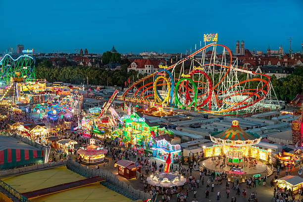 Vibrant evening view of the fairground in Munich featuring illuminated rides, games, and a festive crowd celebrating Bavarian culture, offering an exciting urban amusement experience.