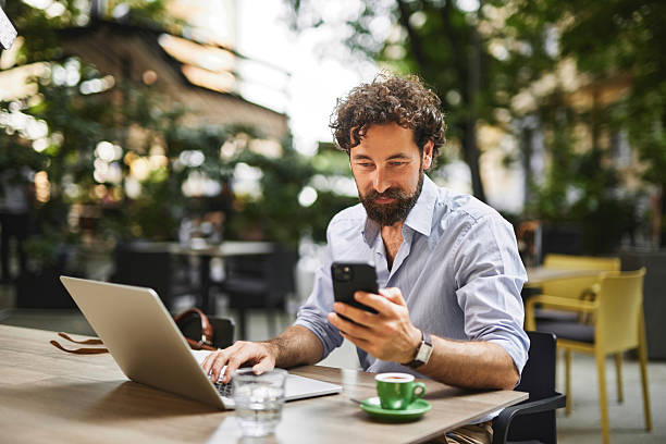 istock Businessman working remotely from a cafe using laptop and smartphone 2234268725