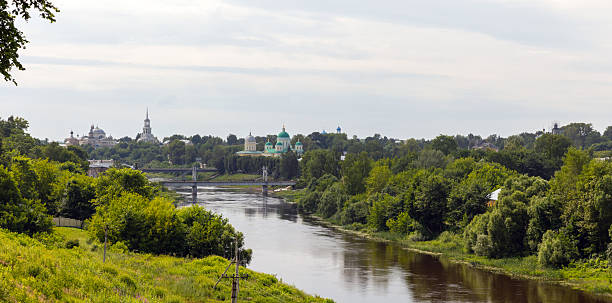 Panoramic tranquil river scene with lush greenery and a city skyline
