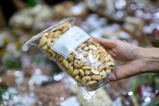 istock Hand holding packed cashew nuts in plastic bag at grocery store 2234269234