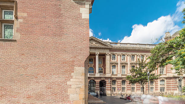 Renaissance dungeon and classical brick facade of the Capitole back side timelapse hyperlapse, city hall of Toulouse, France, surrounded by trees in Charles de Gaulle Square under a cloudy sky