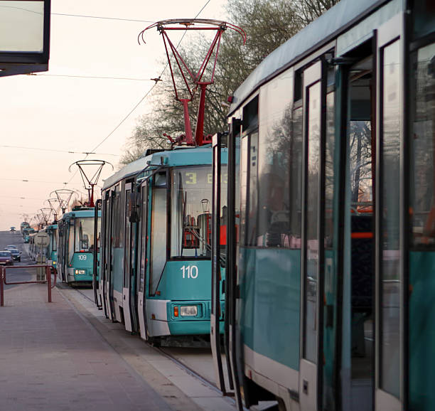 A cyclist rides alongside a blue and white tram as it moves through the city. The street is bustling with activity. Amsterdam Netherlands