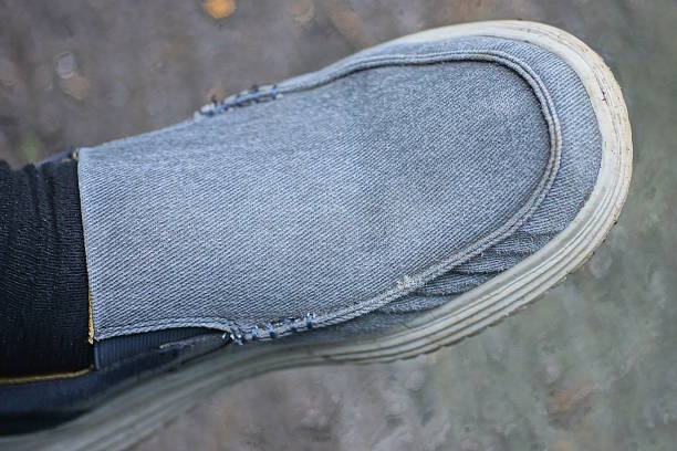 one gray fabric boot with a white sole on a foot with a black toe on a summer street