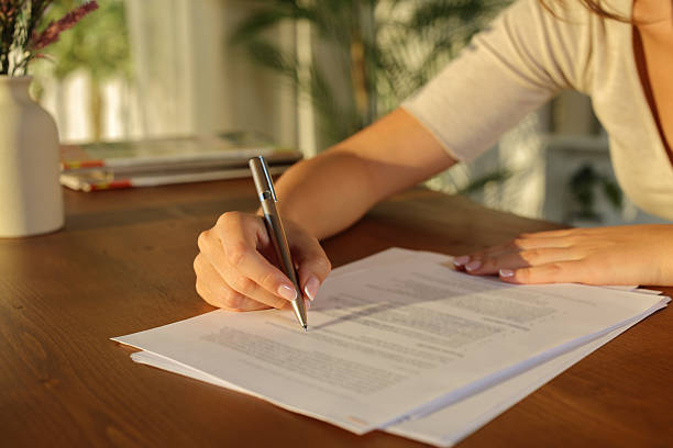 istock Woman hand filling document on wooden table at sunset 2234270096