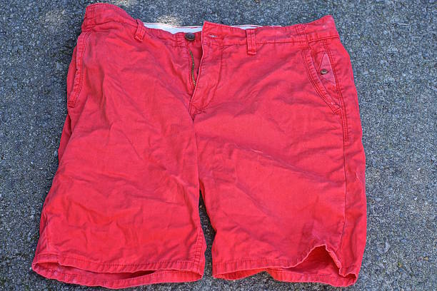 one red fabric beach shorts lies on gray asphalt