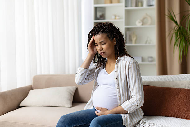 istock Thoughtful pregnant woman sitting on sofa, touching her head with concern 2234275071
