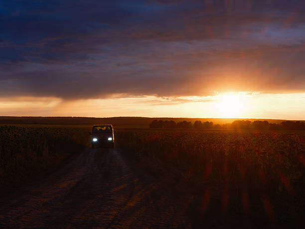 istock Car Driving on a Field Road at Sunset 2234275320