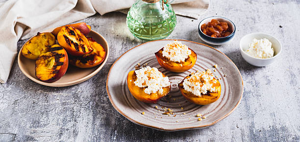 istock Grilled peach halves with ricotta and nuts on a plate on the table web banner 2234275389