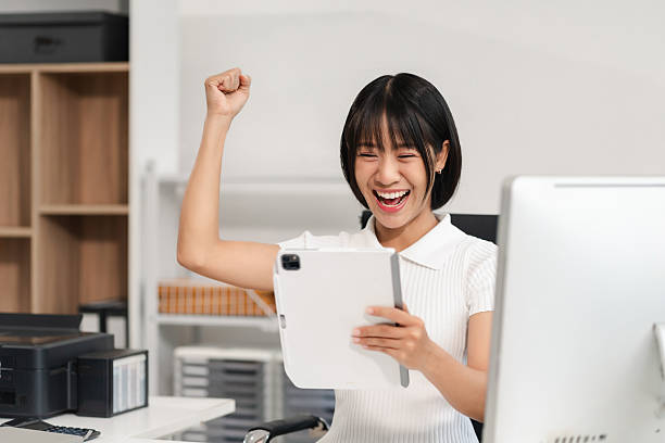 istock Overjoyed charming excited asian woman worker using tablet working in office, feeling happy. 2234276560