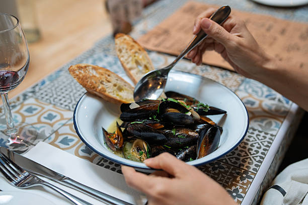 istock Hand holding cooked mussel from seafood dish with bread 2234276814