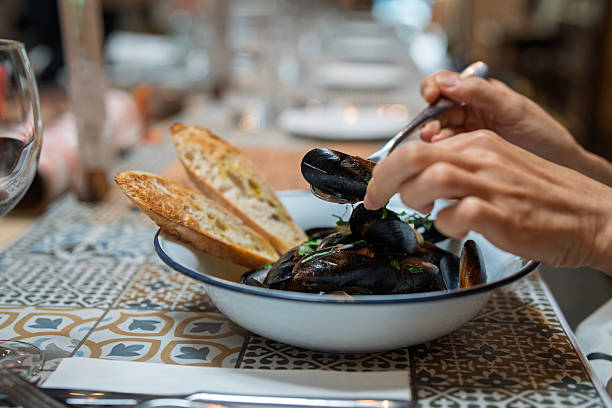 istock Hand holding cooked mussel from seafood dish with bread 2234277259