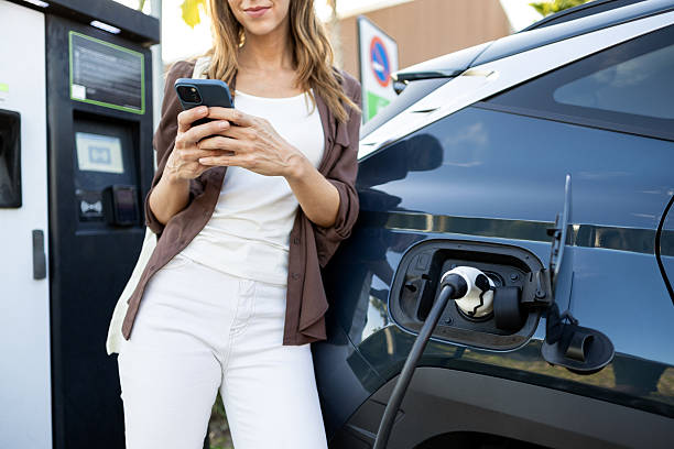 istock Woman using smartphone while charging electric car at station 2234281266