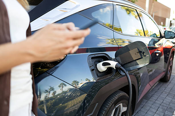 istock Woman using smartphone while charging electric car at station 2234281277