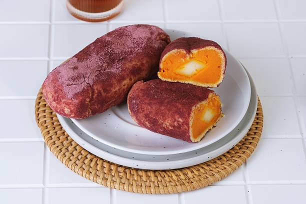 Traditional Korean sweet potato bread with golden filling, sliced and served on white plate.