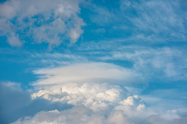 Huge dramatic lenticular cloud on white lush cloudy hill in blue sky. Beautiful cloudscape with big UFO shaped cloud in center. Scenic skyscape with altocumulus clouds. Awesome unusual cloudy skies.