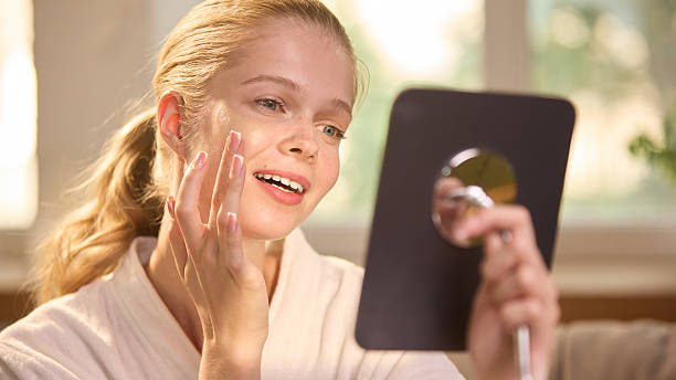 istock Soft glam. Smiling woman applying serum foundation while looking in handheld mirror at home 2234287703
