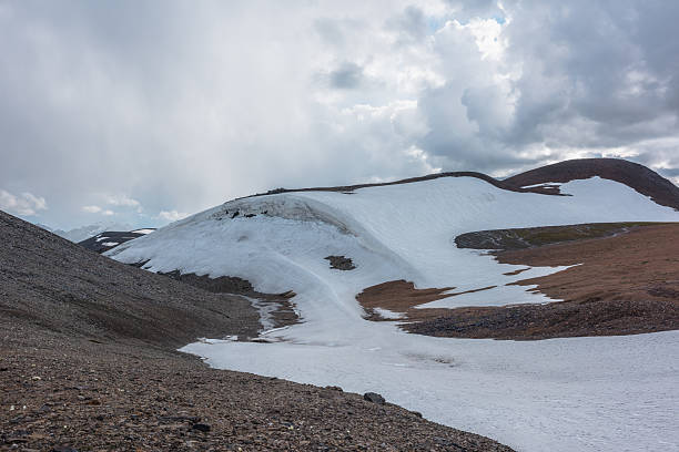 istock Dramatic mountain landscape with water stream along beautiful glacier on stone rock hill under rainy cloudy sky. Alpine valley under snow cornice in rain time in gloomy weather. Atmospheric mountains. 2234288515