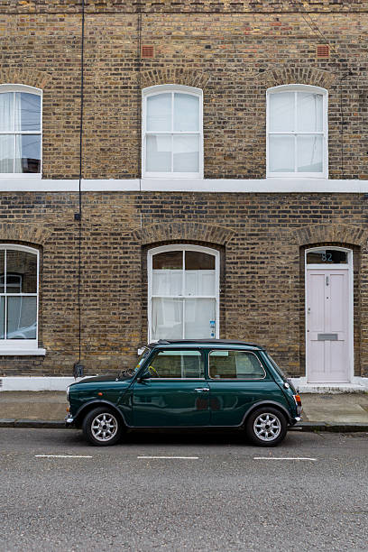 A classic car is parked on a London street. The background, with typical red brick houses, evokes the atmosphere and style of Great Britain.