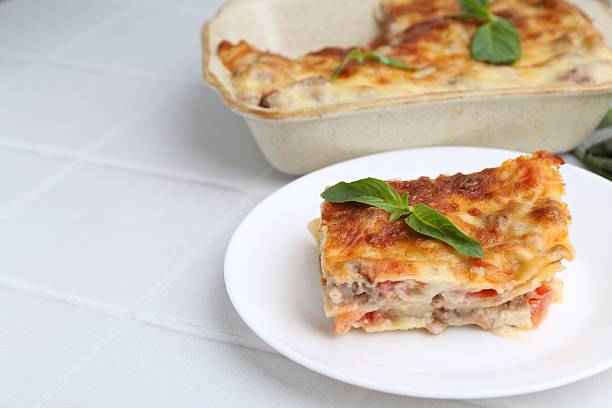 istock Piece of delicious cooked lasagna with basil on white tiled table, closeup. Space for text 2234291046