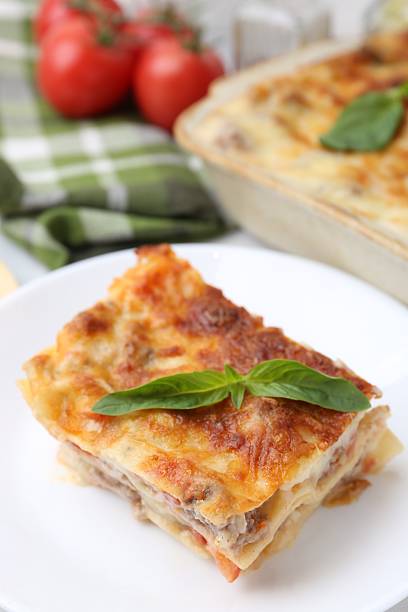 istock Piece of delicious cooked lasagna with basil on table, closeup 2234291124