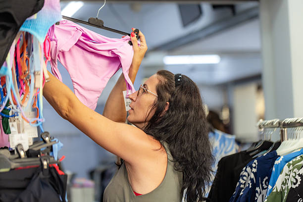 Young blonde woman chooses swimsuit for herself in a shopping mall store