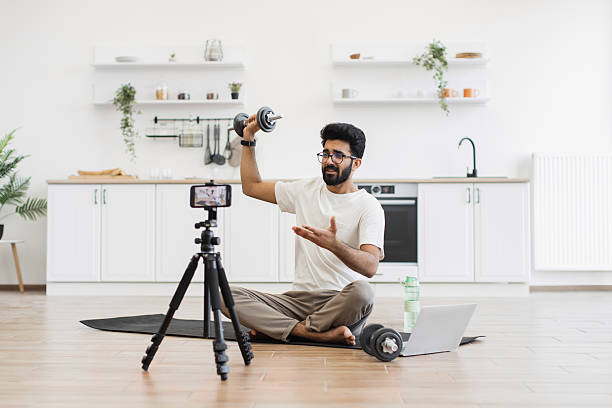 istock Man creating fitness blog about home workout techniques with dumbbells 2234294199