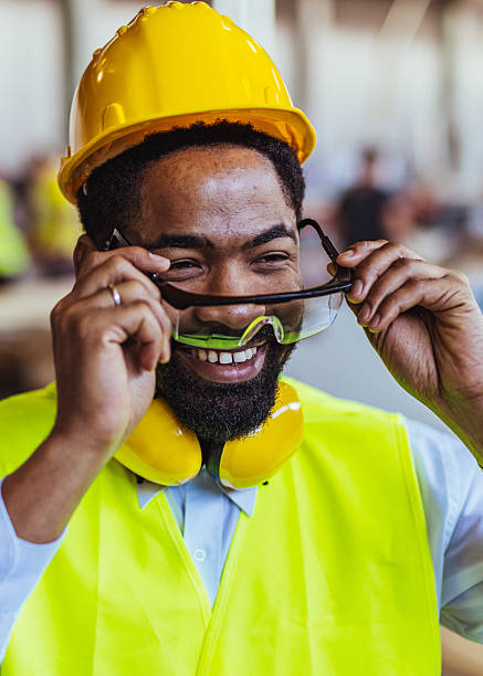 istock Smiling Construction Worker Wearing Hard Hat and Safety Goggles on Site 2234294367