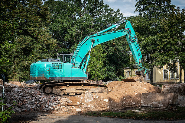 Large turquoise excavator working on a construction site with piles of soil and debris. Demolition, industry, and urban development.