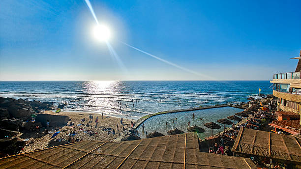 Against the rhythmic patterns of the pergola man with backpack standing, absorbing the calm energy of the sea