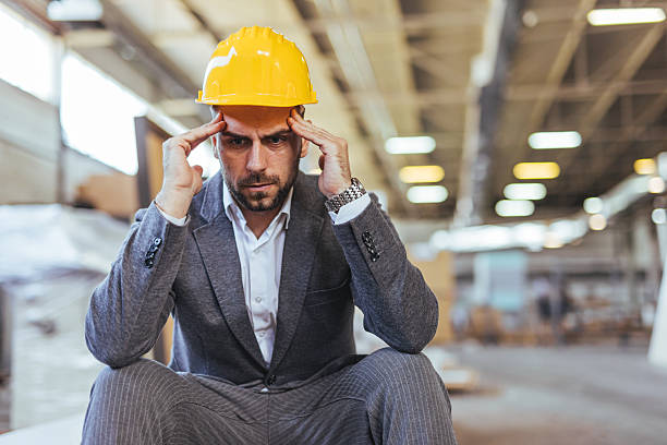 istock Frustrated Businessman Wearing a Hard Hat in an Industrial Setting 2234298259