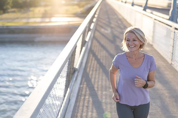 istock Smiling woman jogging on a bridge during sunrise with river view. 2234301486