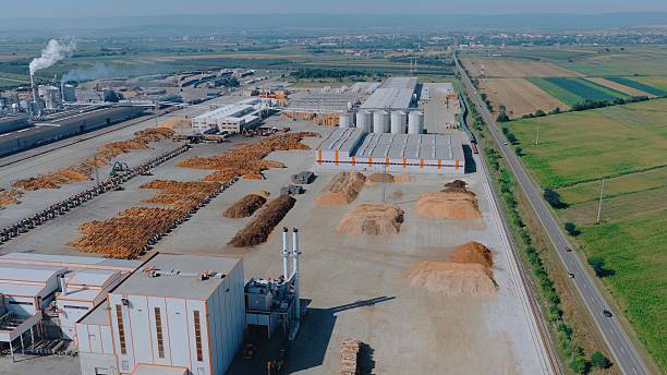 istock Lumber factory processing wood and producing smoke from chimneys 2234302578
