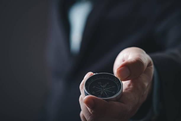 istock A hand holds a compass, symbolizing direction and guidance, set against a dark background. 2234304184