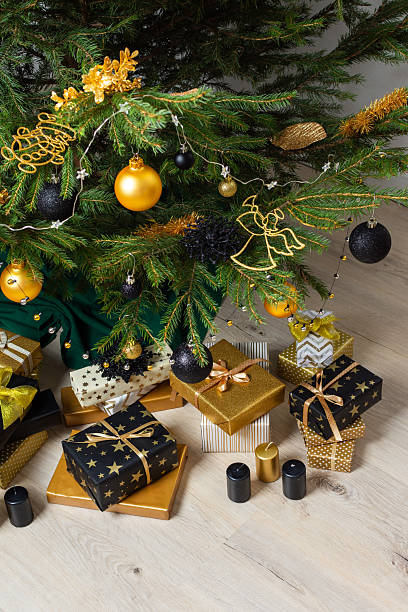 istock A festive scene featuring gold and black gift boxes, surrounded by shimmering candlelight and stylish decorations under a beautifully decorated Christmas tree, exuding elegance and charm 2234309427