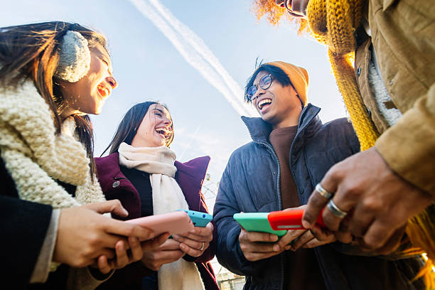 Young group of people in warm clothes using mobile phone device on winter. Social media and technology lifestyle concept