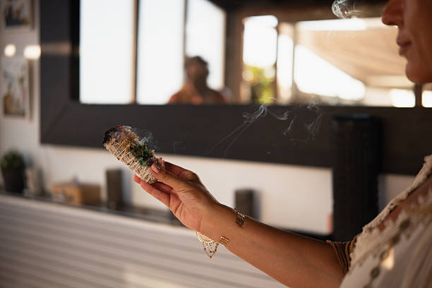 Woman practicing breathwork using a smoking white sage smudge stick during a spiritual ritual