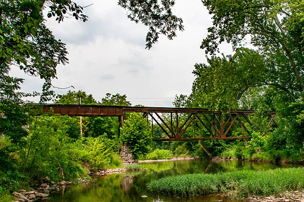 istock Rusty Bridge Crosses Serene River Surrounded by Lush Greenery in Peaceful Landscape 2234317767