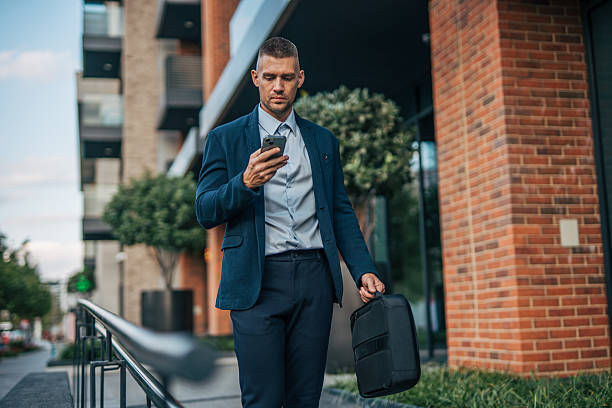 istock Businessman walking and using smartphone in urban setting 2234322727