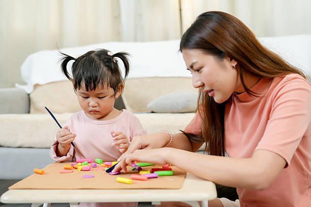 istock Asian single mother helping little daughter shape colorful clay pieces using creativity building skills sitting together on floor cozy bright home early childhood education learning 2234322979