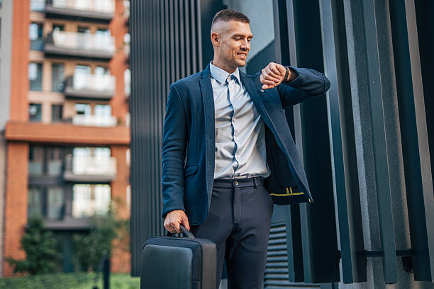 istock Businessman checking time while walking near office building 2234323391