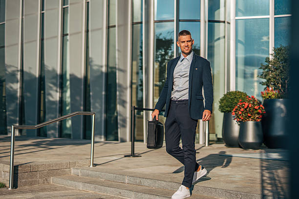 istock Businessman walking down steps in front of modern office building 2234324434