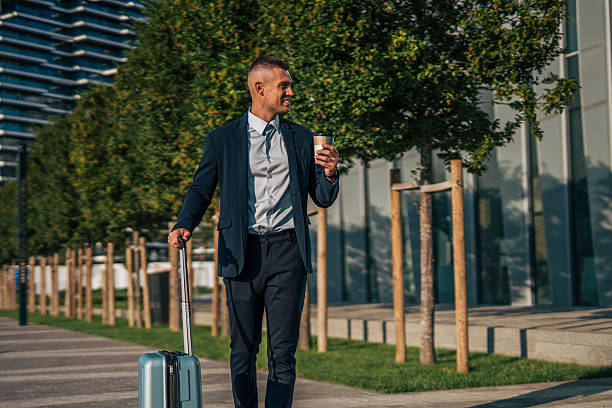 istock Businessman walking with suitcase and coffee in urban setting 2234324650