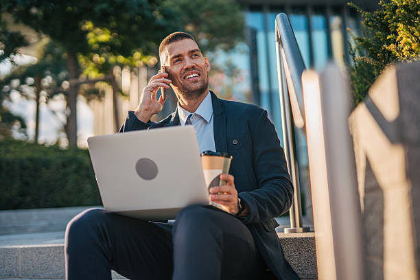 istock Businessman working remotely on laptop and talking on phone 2234327567