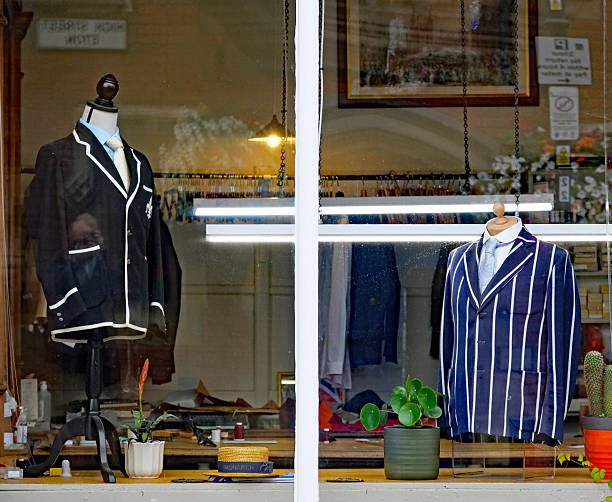Eton High Street, Berkshire, United Kingdom, August 16, 2025. Tailors shop window with blazer or jackets and reflections. Near Eton college. Overcast summer day outdoors.